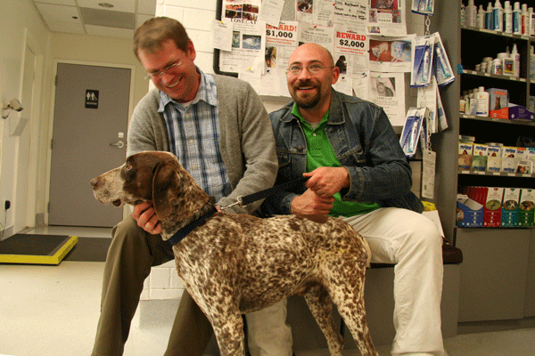 Two men waiting at a veterinary office with a GSP