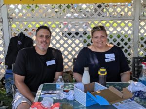 Two volunteers sitting at a table at an event, an example of volunteering