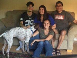 Walker2 with his new family, with 3 people on the couch and one person on the floor next to him