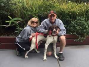 Beamer in front of ferns with his new mom and dada
